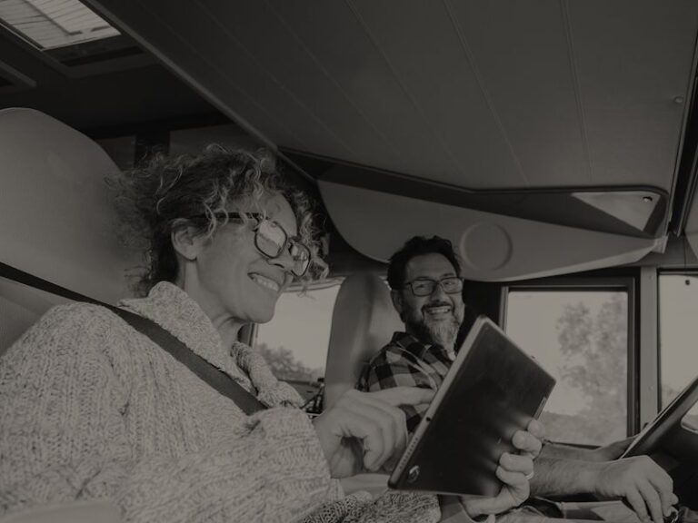 deux personnes dans un camping car qui voyagent avec une tablette à la main